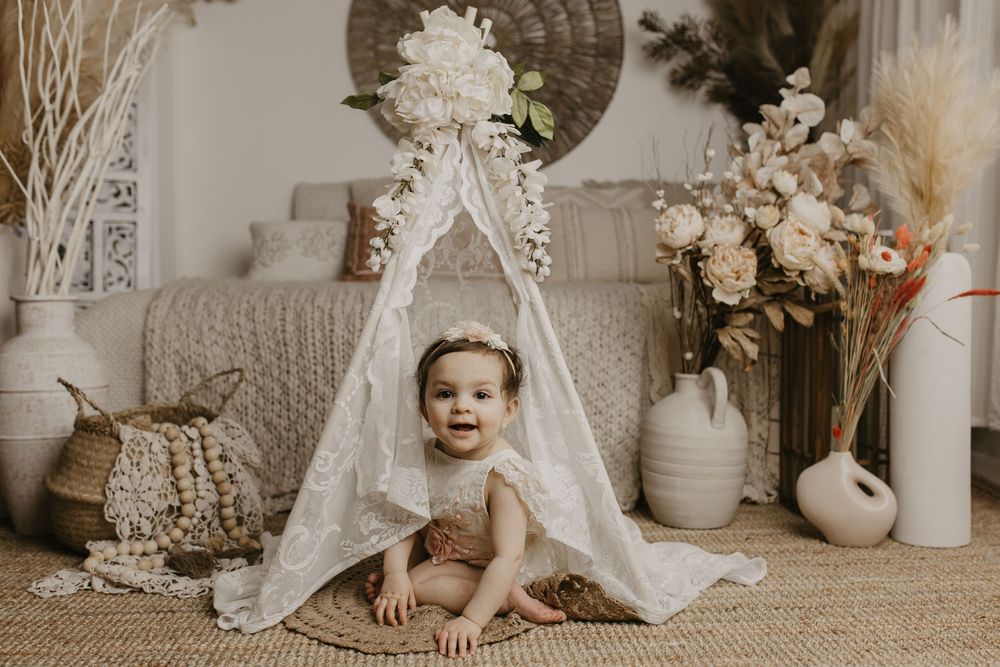 A collage of vintage-toned baby photos featuring lace dresses, floral arrangements, and soft neutral decor elements.