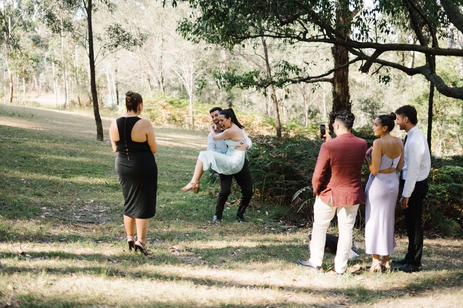 Wedding guest lifting his partner with friends laughing, capturing a fun, candid moment in Daylesford, Victoria—2 hours from Melbourne.