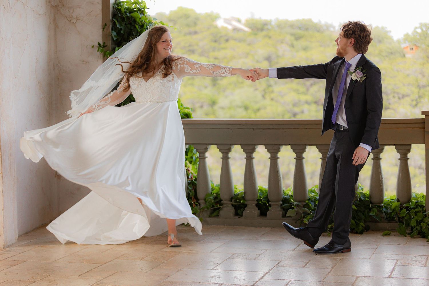 A playful wedding moment on a balcony with flowing white dress movement.