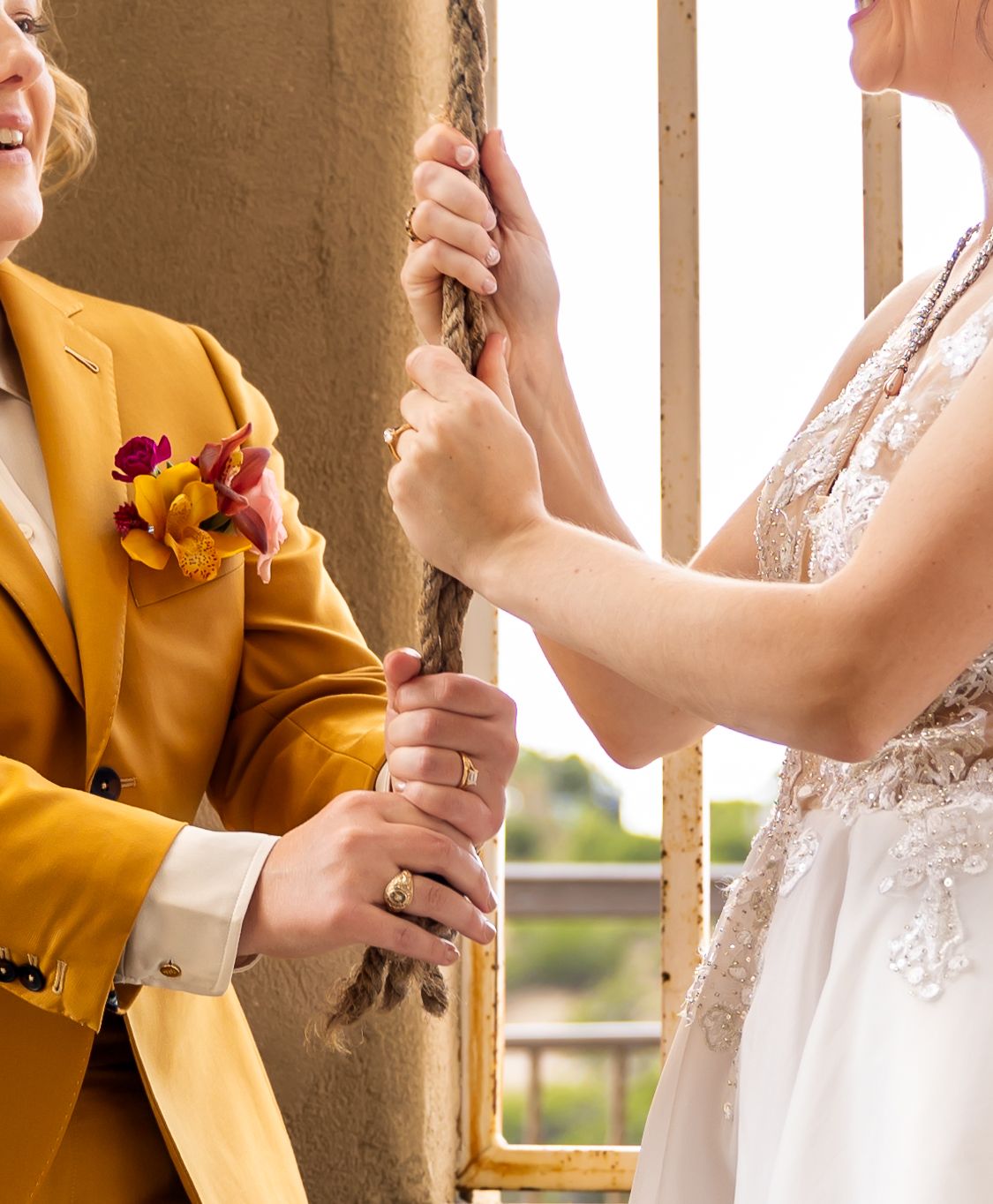 A couple sharing a playful moment at their wedding with one wearing a vibrant yellow suit.