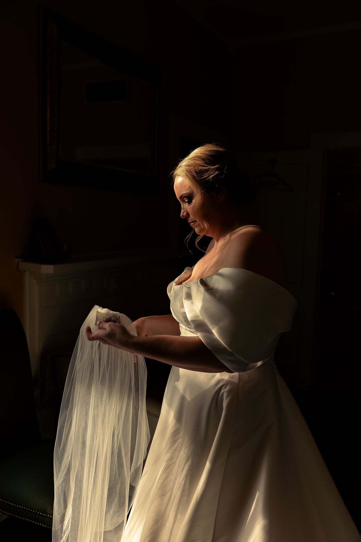Dramatic lighting captures a wedding dress silhouette in a dark room.