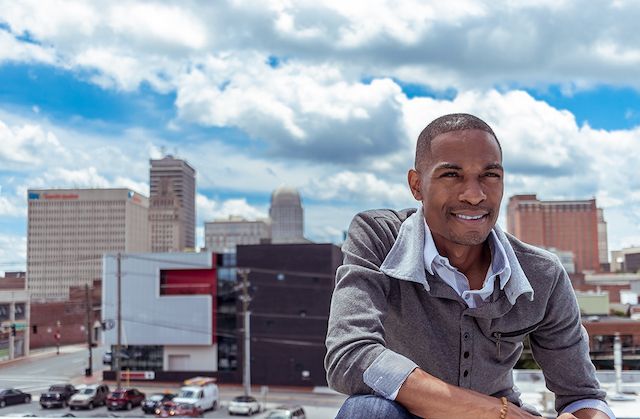 Urban rooftop portrait with city skyline and blue cloudy sky in background.