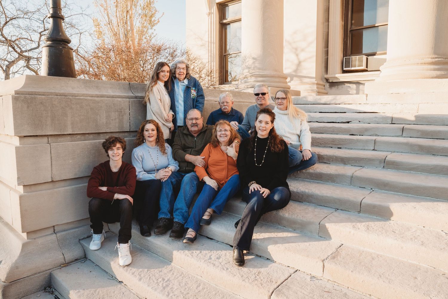 Family portrait. 10 members. 4 generations.  On the steps of a building, smiling and looking at the camera. Doughman Photography