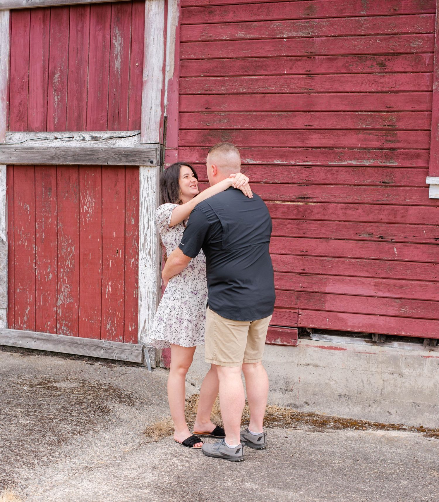 Couple performing dance sequence outside red barn wall.