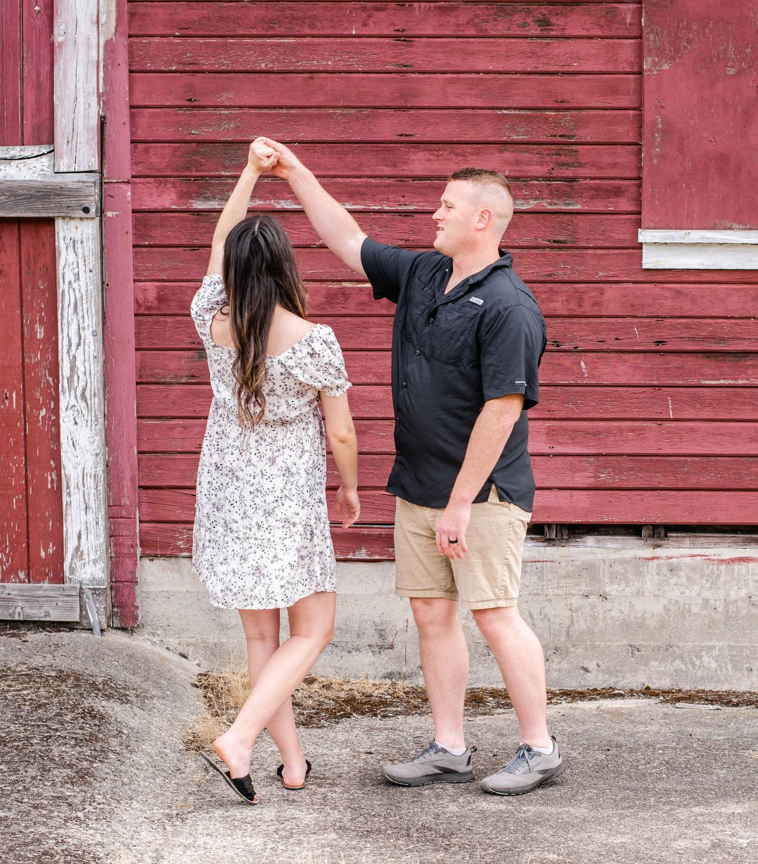 Dancing couple practicing steps together by weathered red barn siding.