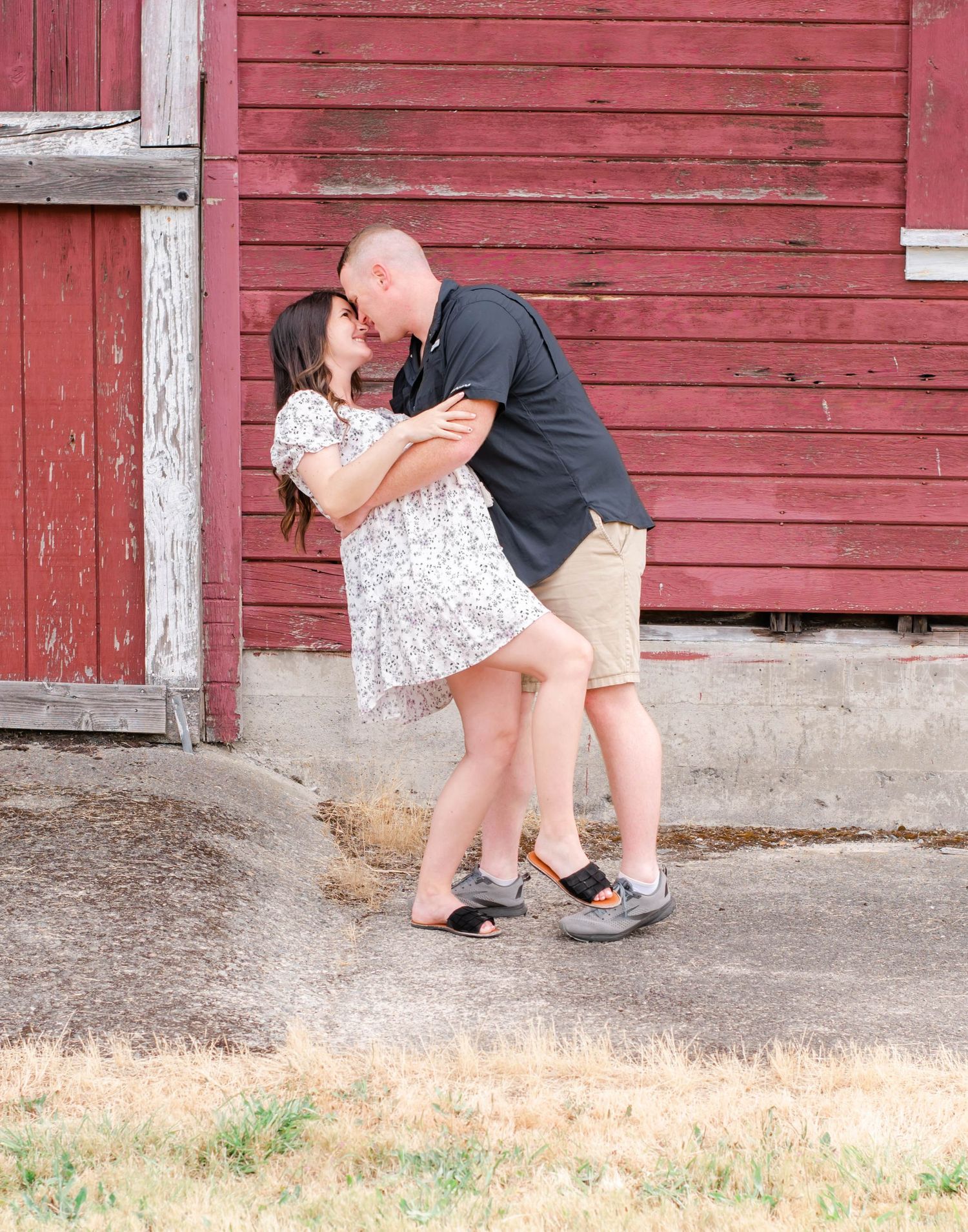 Dance partners practicing steps and poses along rustic barn wall.