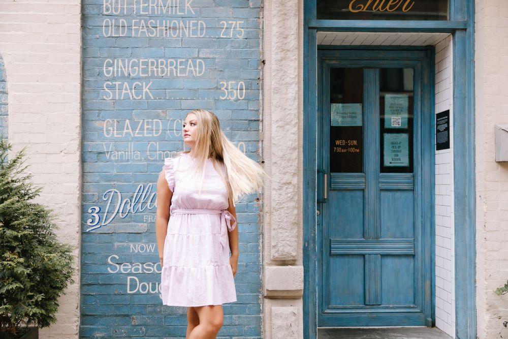 A pink dress contrasts against blue painted menu wall and vintage doorway.