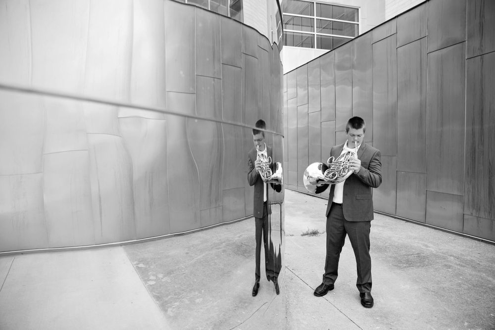Black and white photo of musicians performing between industrial metal walls.