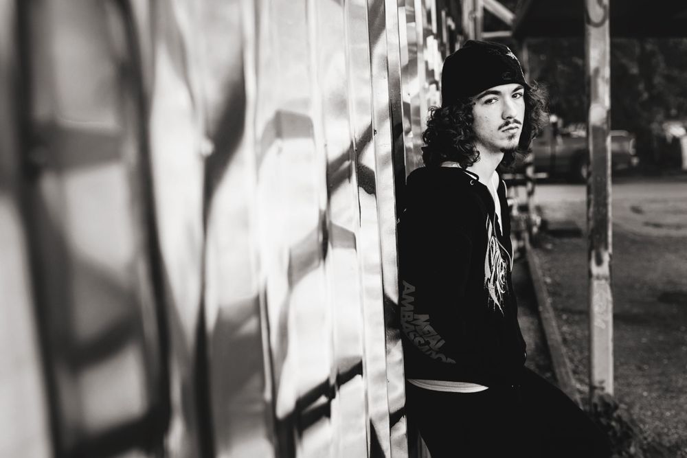 Black and white portrait showing dramatic shadows and lighting against textured wall.