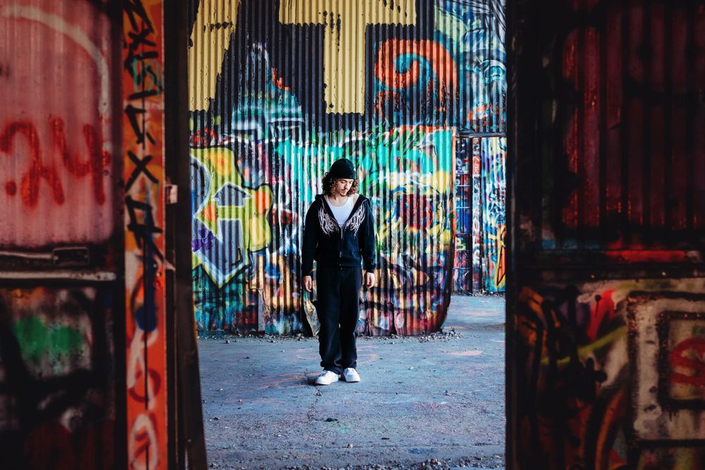 Silhouette walking through graffiti-covered urban alley with bright street art.