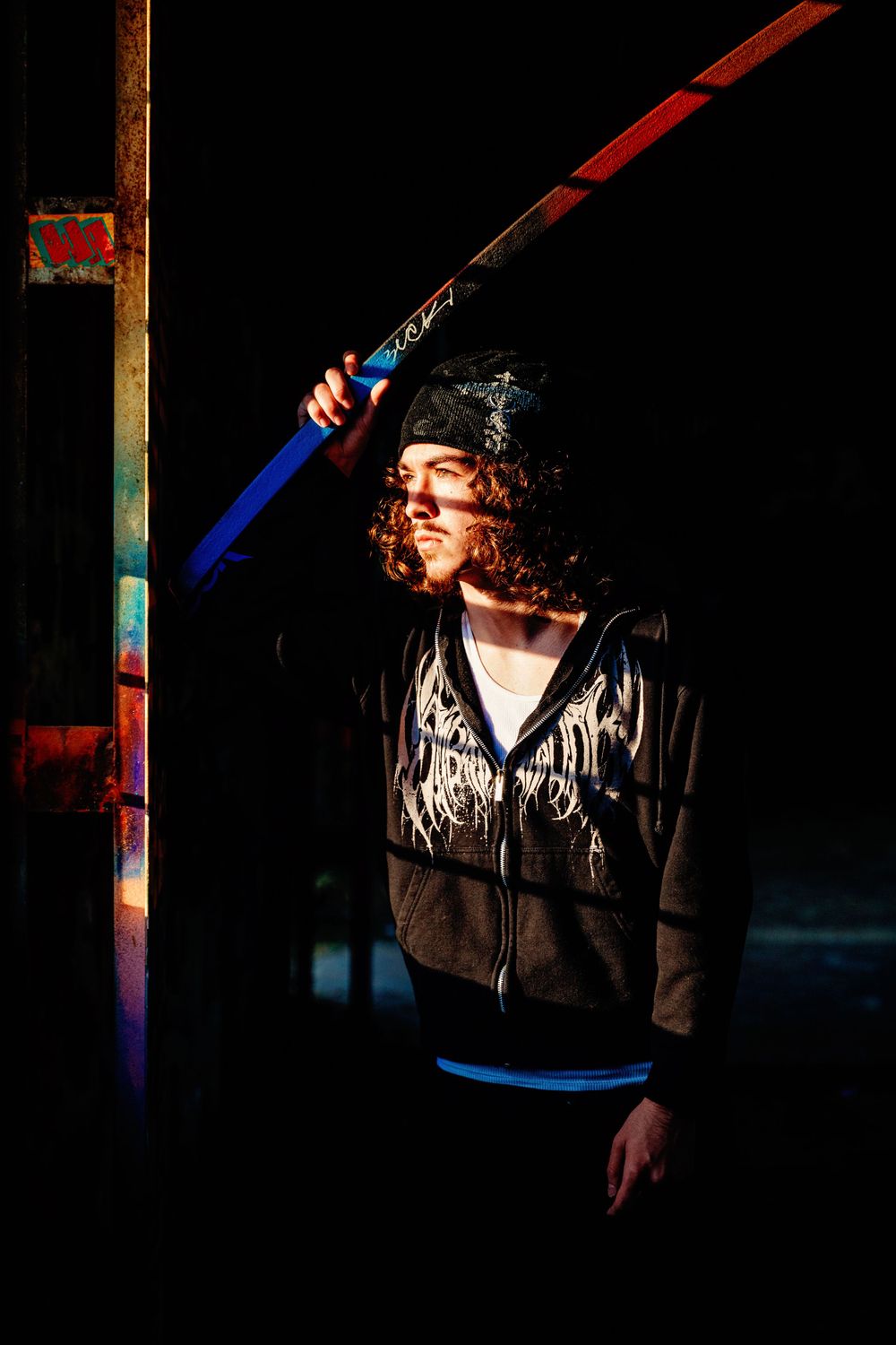 Dramatic portrait in dark setting with neon lighting and sports equipment.