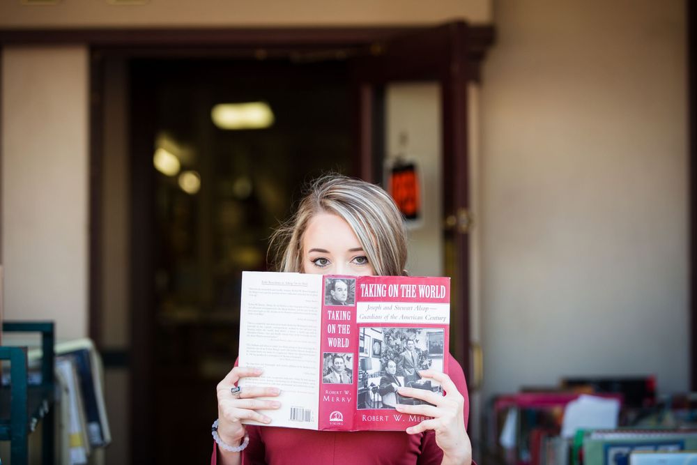 Someone holding up vintage books while standing in a doorway with warm lighting.