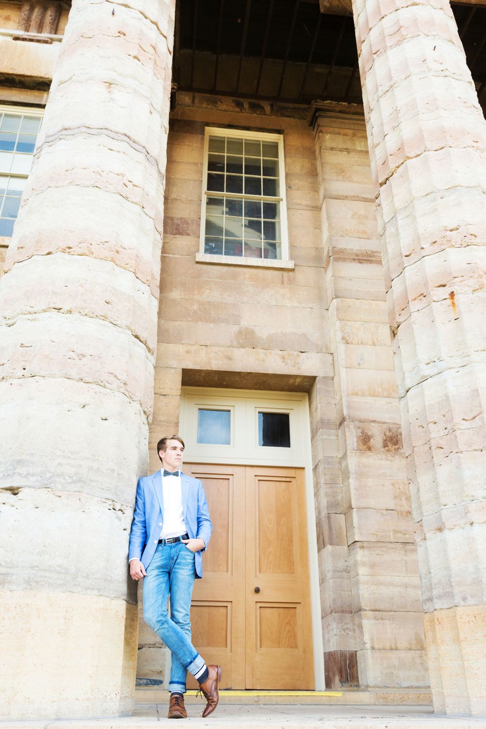 Casual portrait against limestone columns and wooden door of historic building architecture.