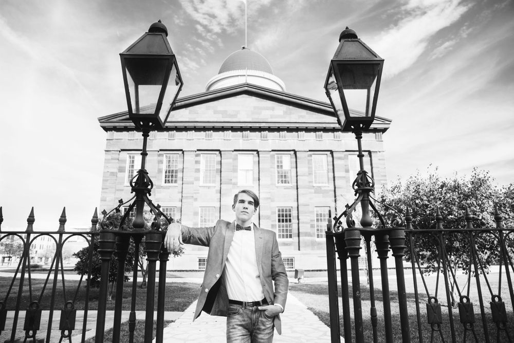 Black and white architectural photo with ornate lampposts framing a historic building entrance.