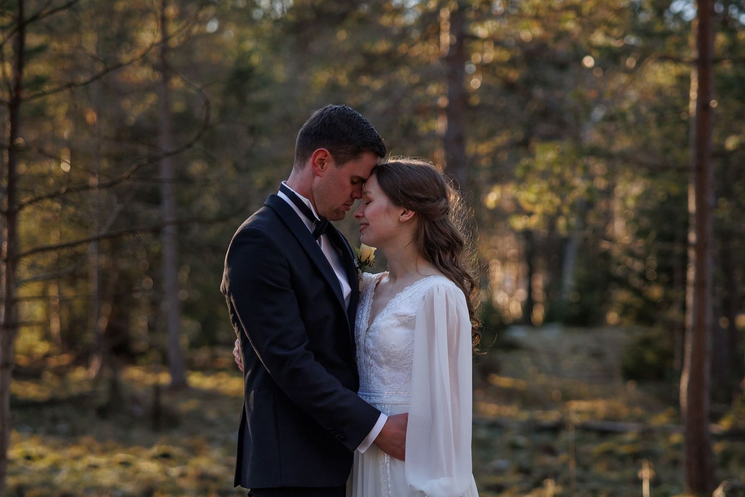 Intimate wedding portrait in a golden sunset forest setting.