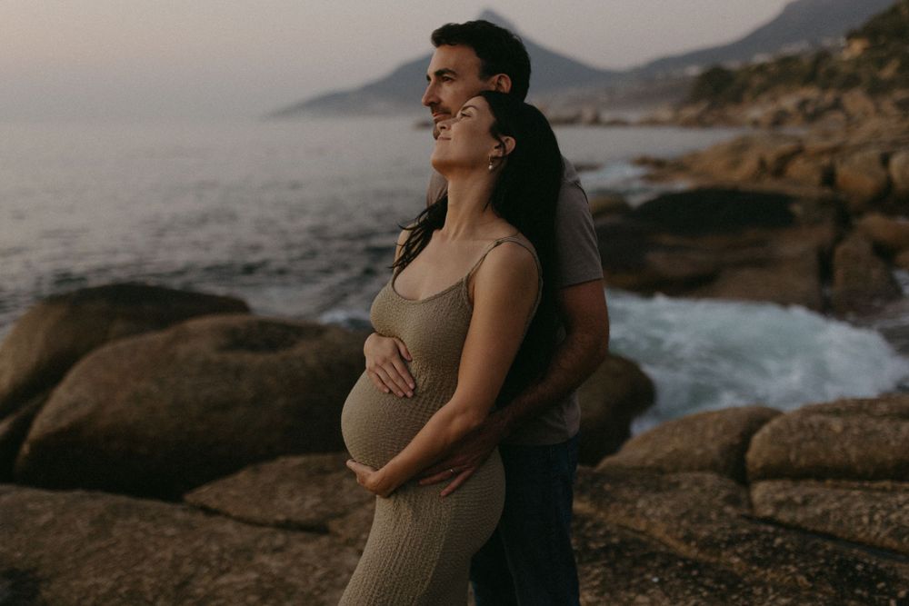 Intimate maternity photos captured against dramatic coastal landscape.