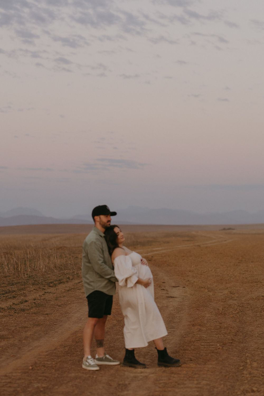 Couple shares intimate moment in desert landscape during golden hour.
