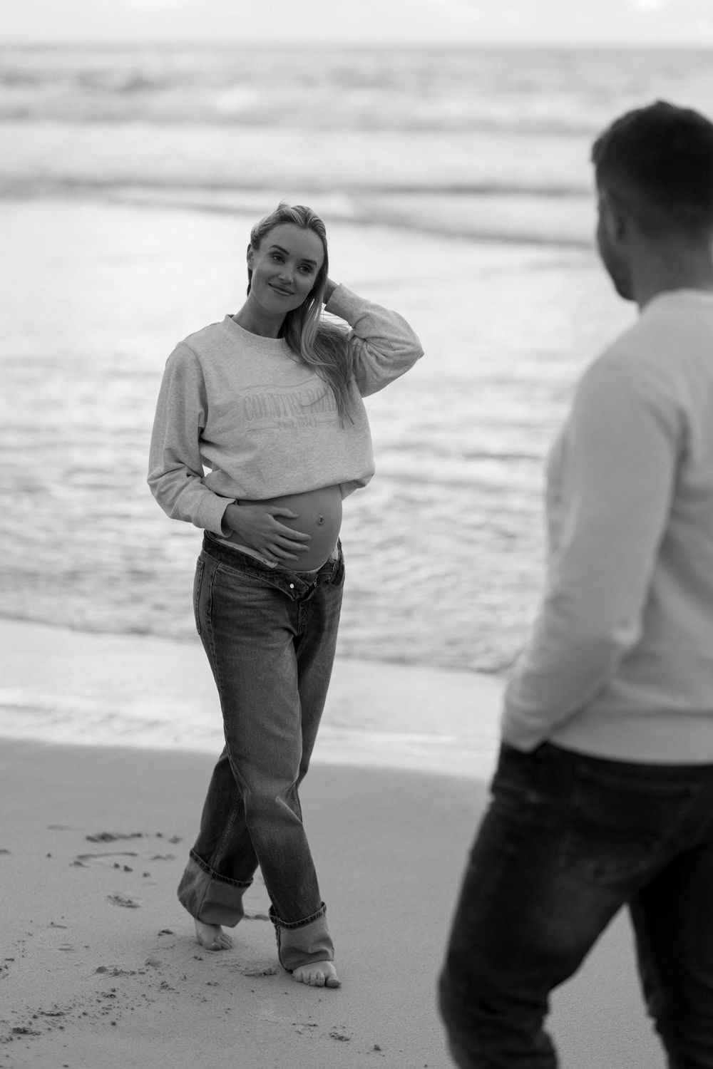 Black and white sequence of photos showing playful interaction between two people on a sandy beach.