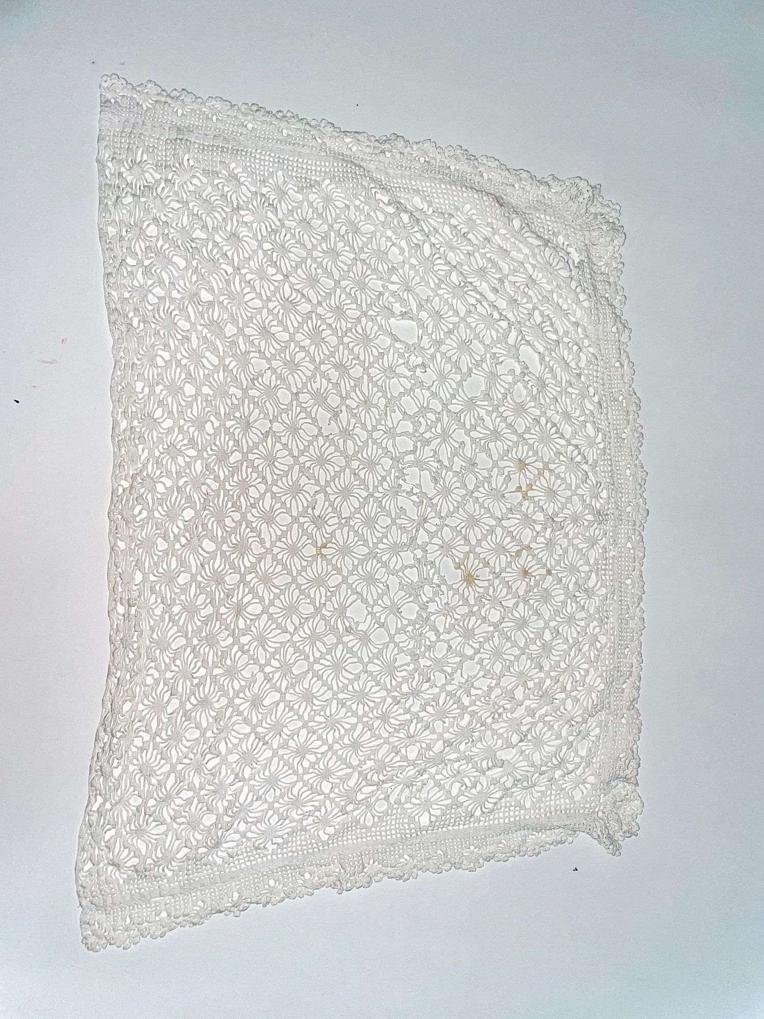 Vintage white lace fabric with delicate diamond pattern displayed against light background.