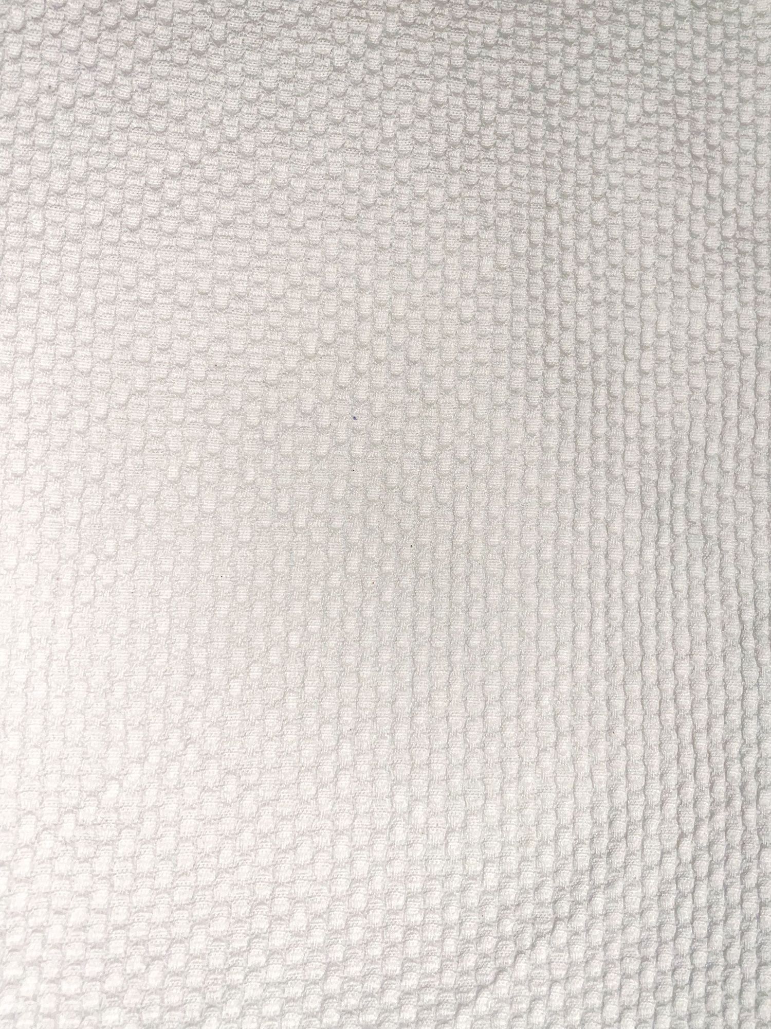 Close-up texture of white woven fabric with regular geometric pattern.