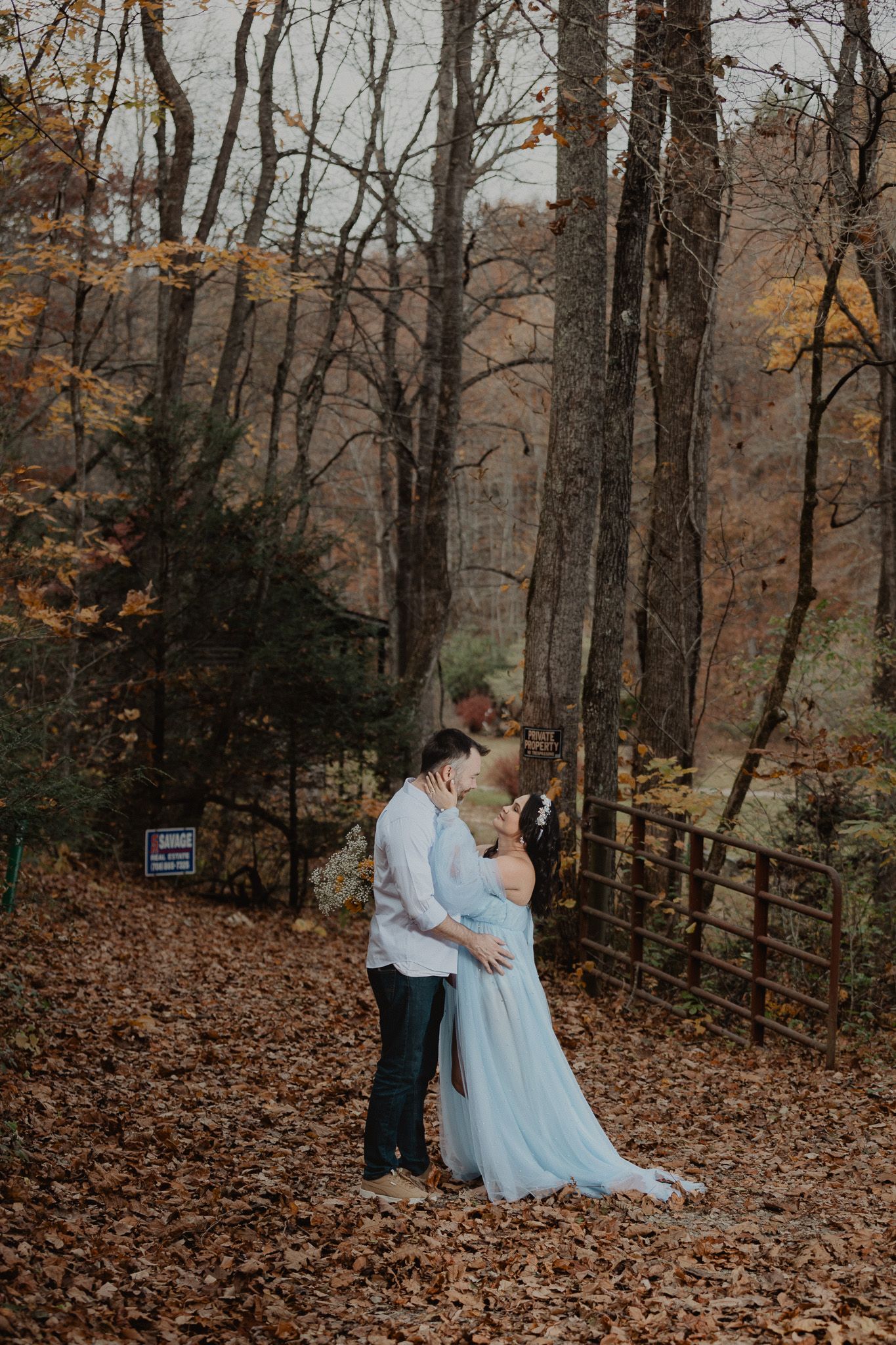 Fall engagement photos with couple in blue dress surrounded by autumn foliage.