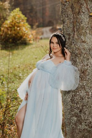 Light blue vintage-style dress photographed against autumn trees and natural backdrop.