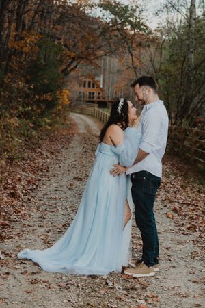 A romantic maternity photo session on a leaf-covered path in autumn.