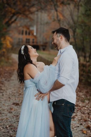 A couple embraces during their maternity photoshoot on fallen autumn leaves.