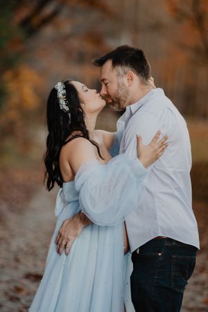 Romantic couple in light blue dress and white shirt sharing intimate moments in a fall setting.