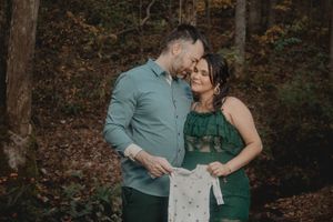 A couple shares tender moments during their maternity shoot in green outfits.