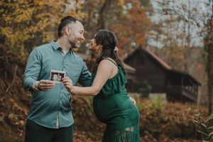 A couple in coordinated green outfits shares a tender moment during their maternity session.