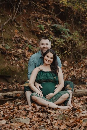 Couple's portrait session showing tender moments while sitting in fallen autumn leaves.