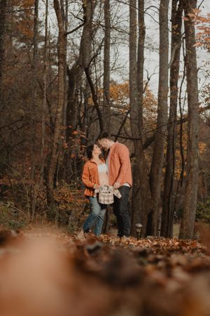 A romantic autumn photoshoot in a forest with warm orange tones and fallen leaves.