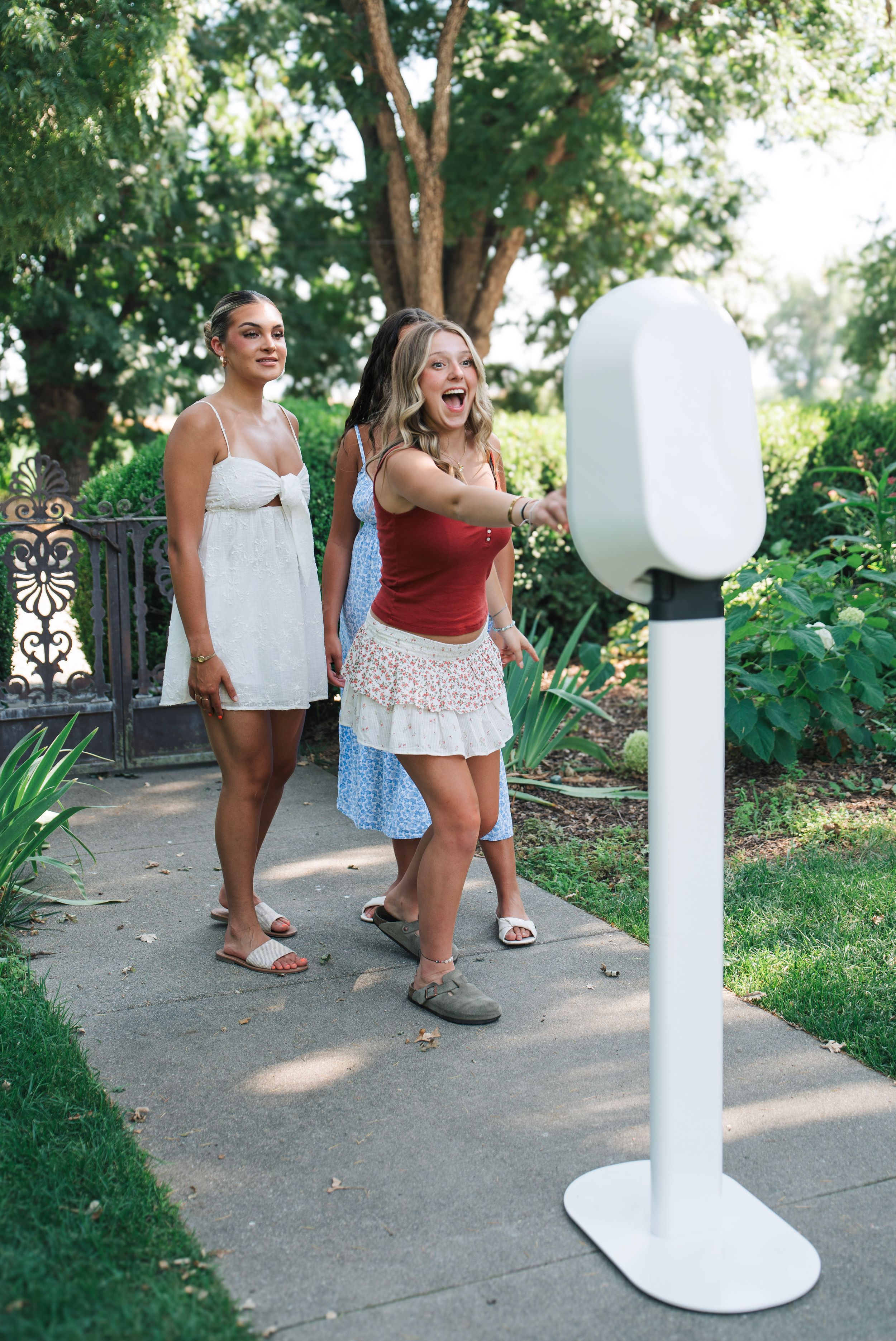 Three girls use a photobooth to showcase how and when to use it at an event