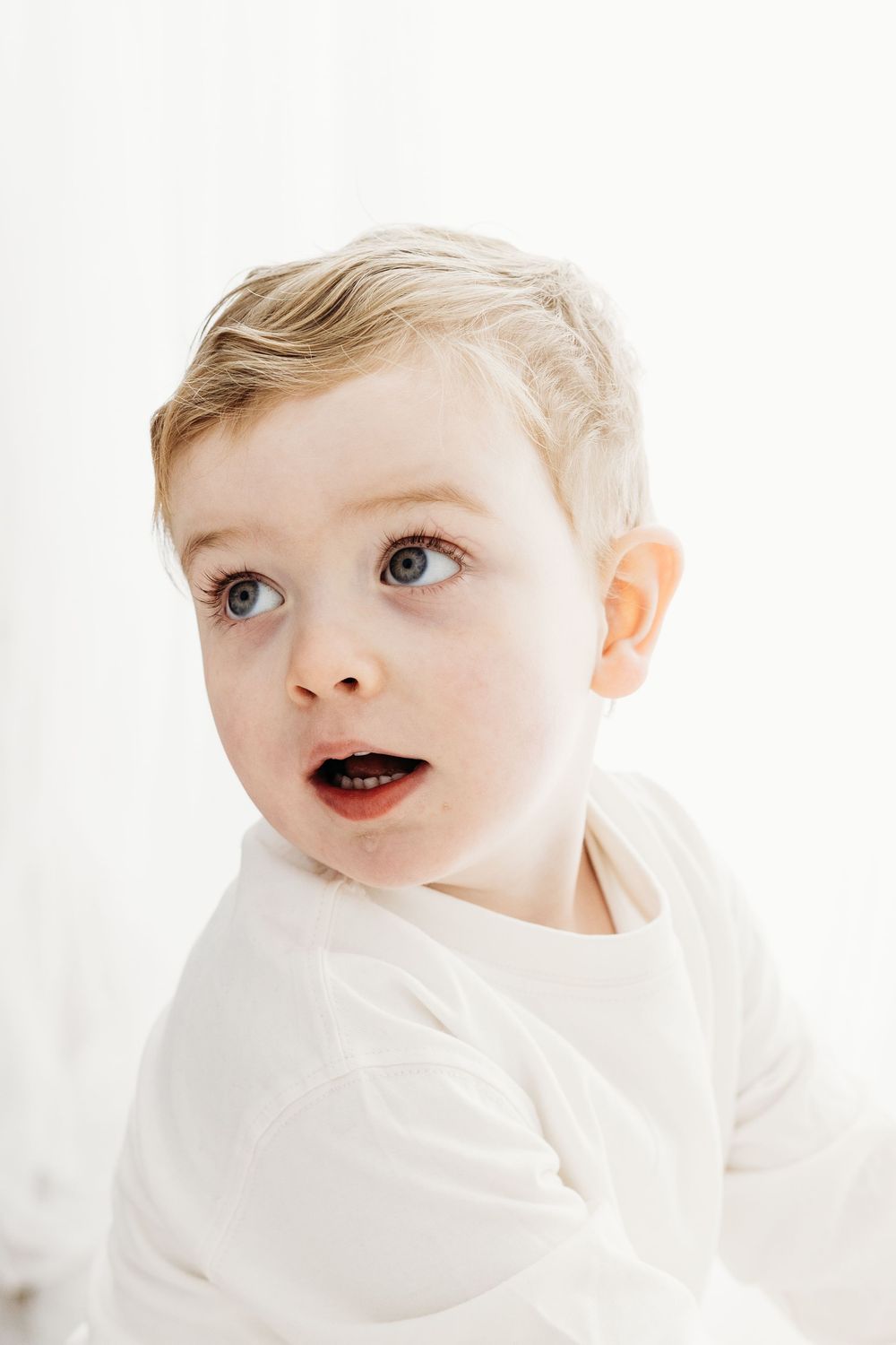 Happy toddler laughing while playing in a minimal photography studio.