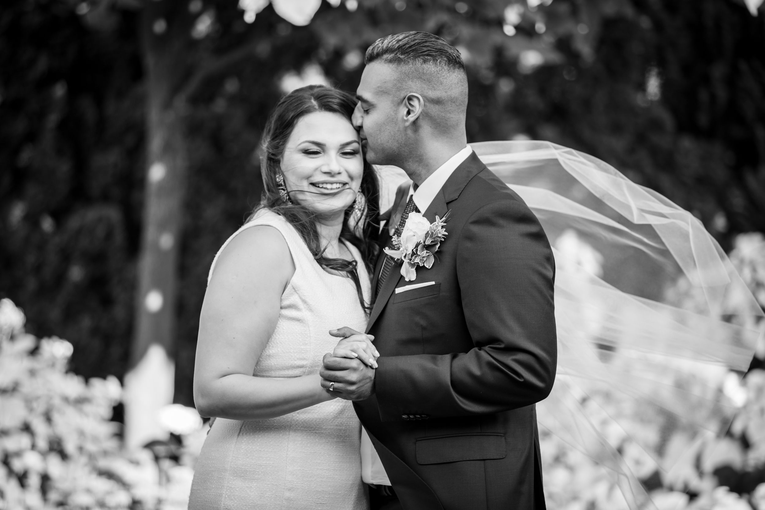 A newlywed couple shares a romantic moment as the groom kisses his bride's cheek.