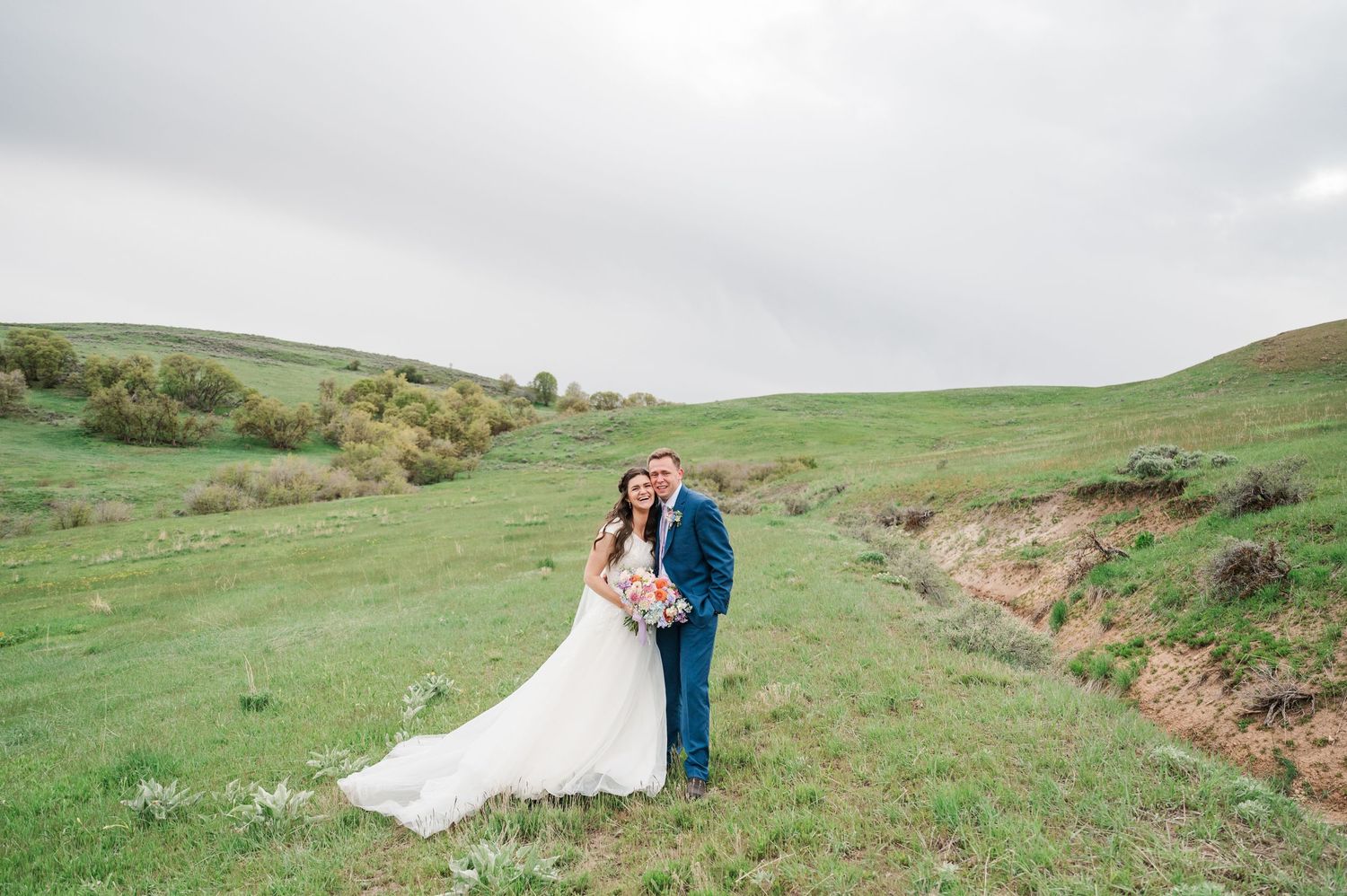 Wedding couple standing in misty green countryside hills.