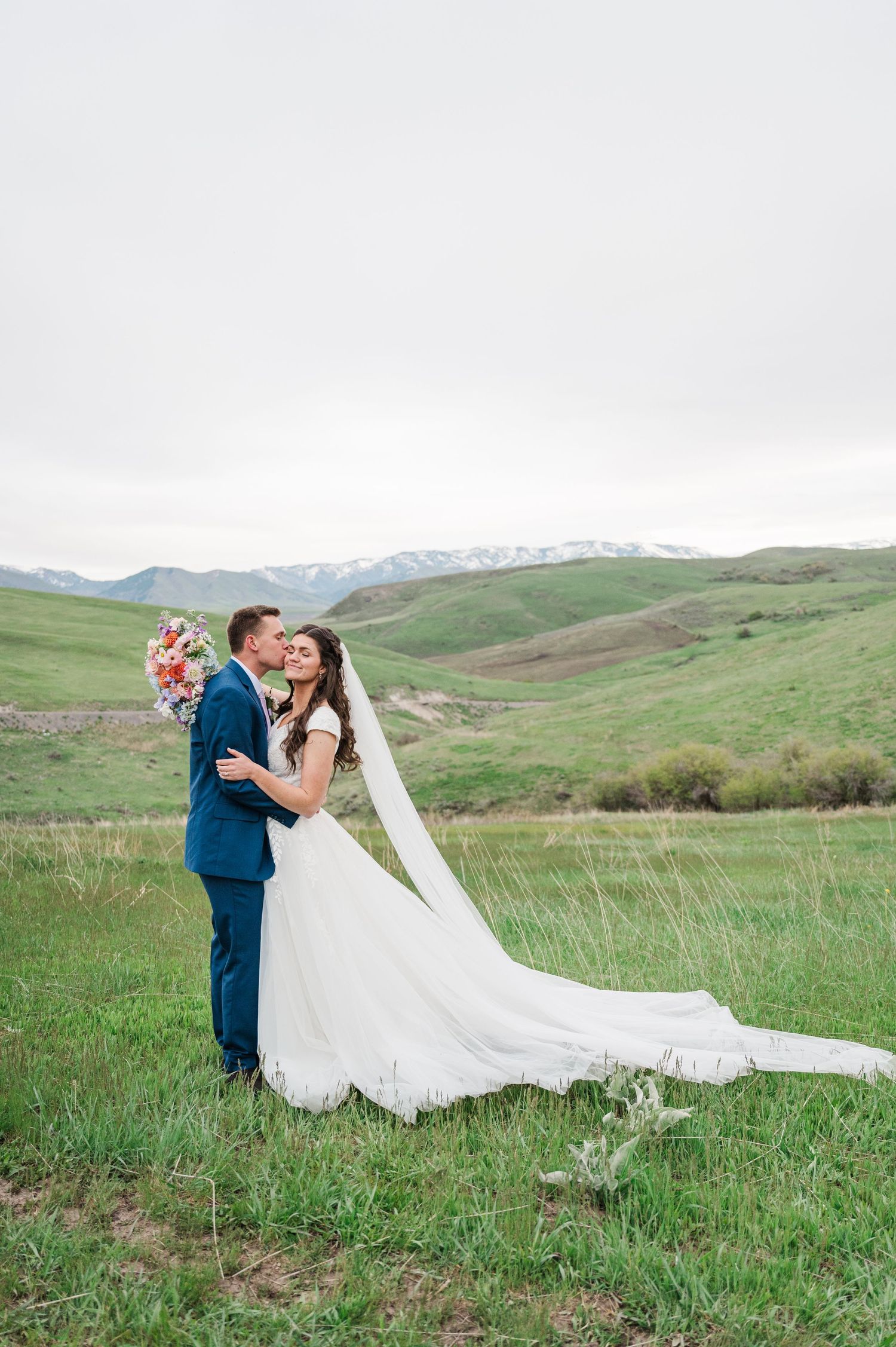 Romantic wedding portrait with snow-capped mountains in background and flowing veil.