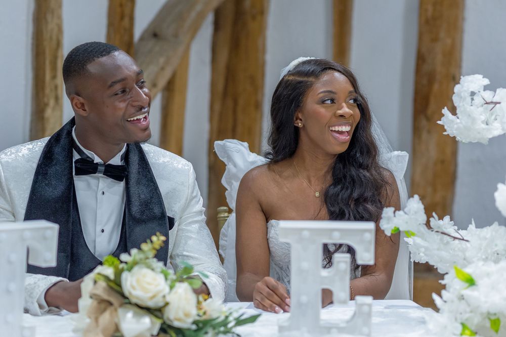 A couple sharing joyful moments at their wedding reception table decorated with white flowers.
