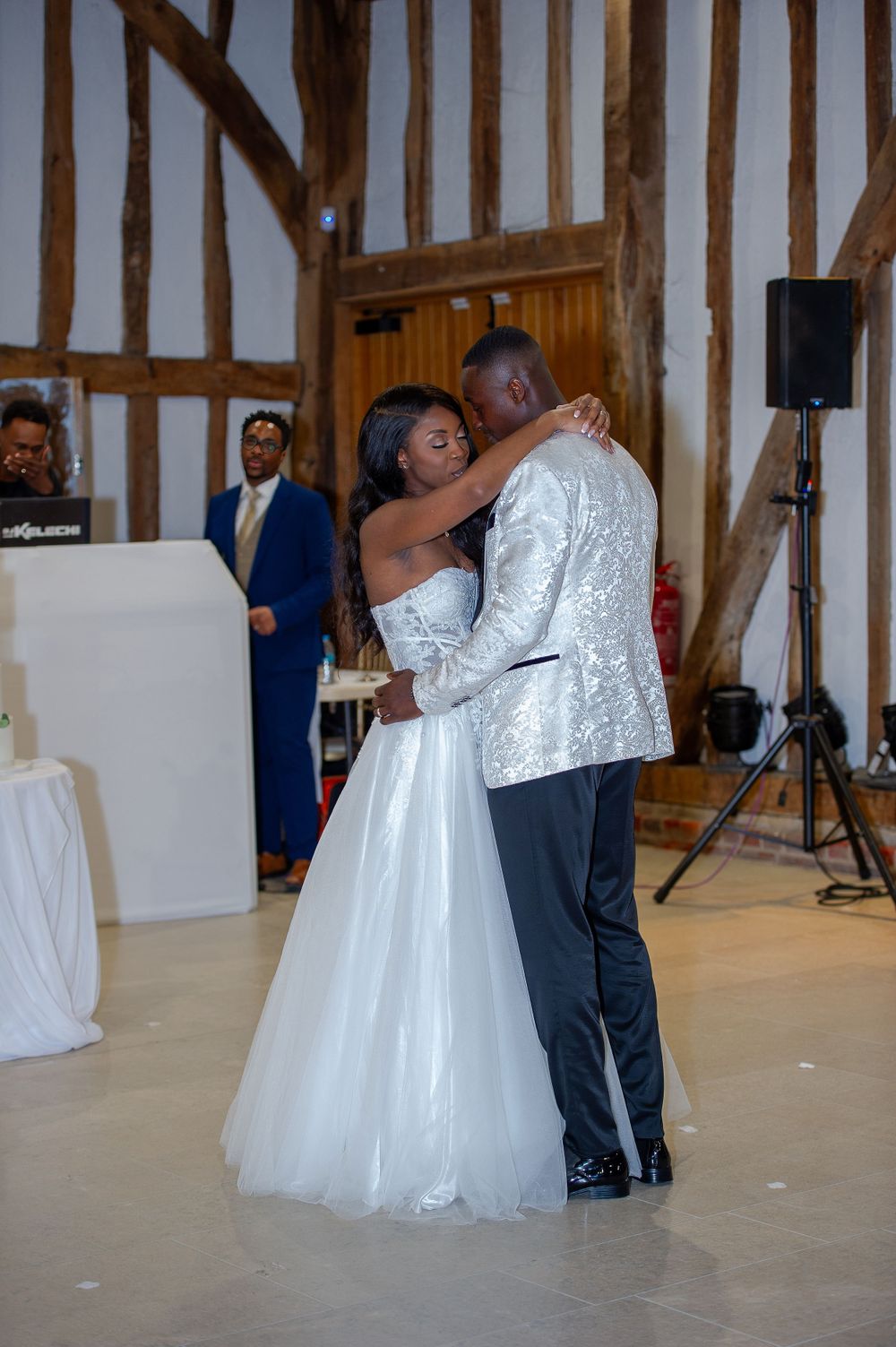 A couple sharing their first dance in an elegant timber-framed wedding venue.