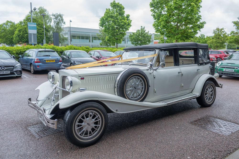 Vintage silver luxury car parked on driveway during wedding celebration.