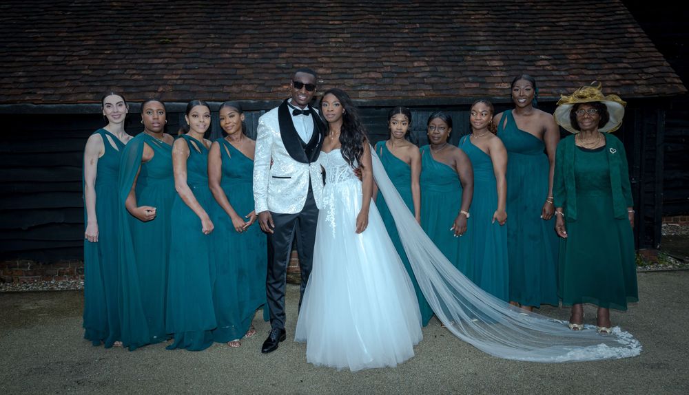 Wedding party wearing teal bridesmaid dresses and white gown posing together outdoors.
