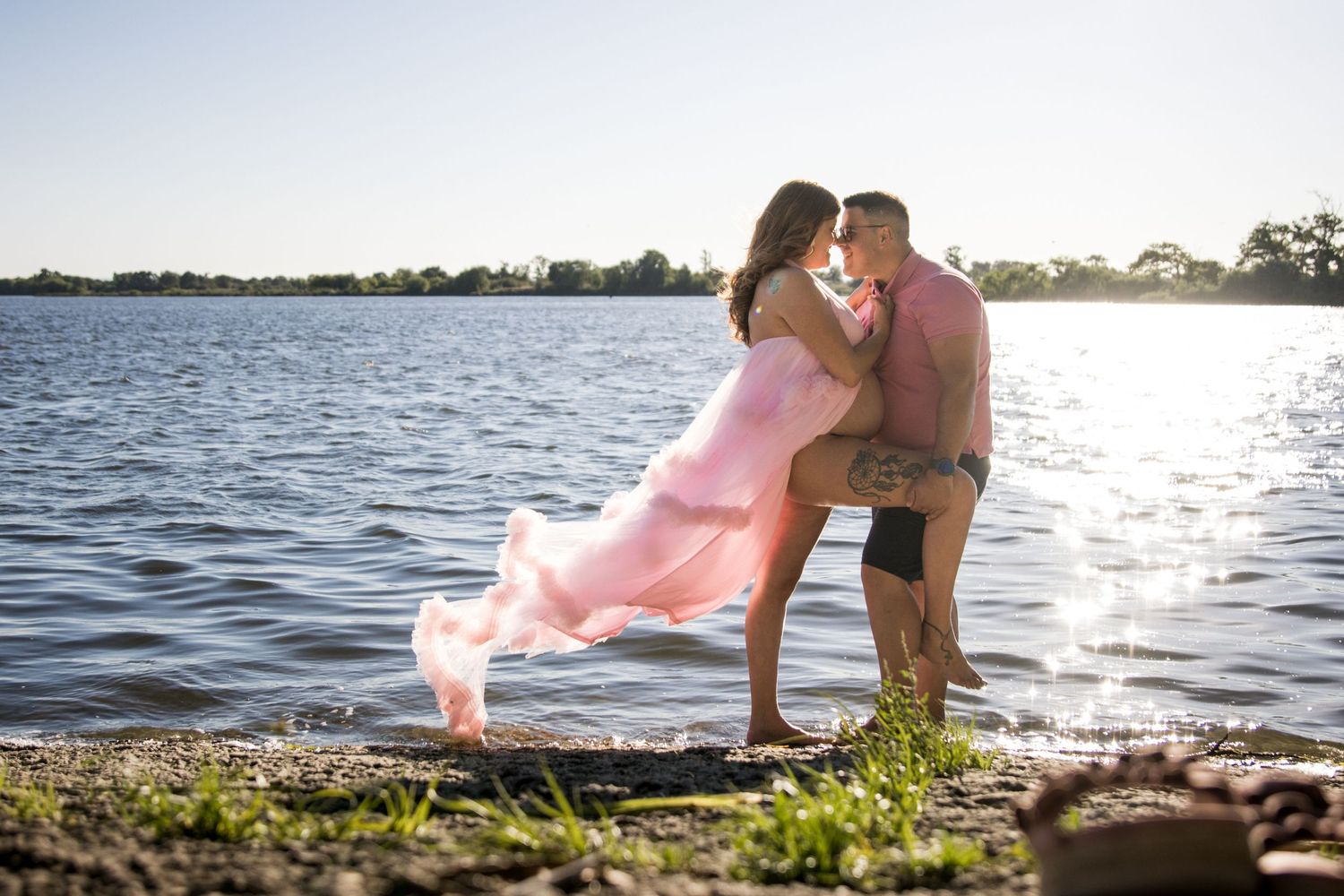 Romantic couple silhouetted against sunset at waterfront location.
