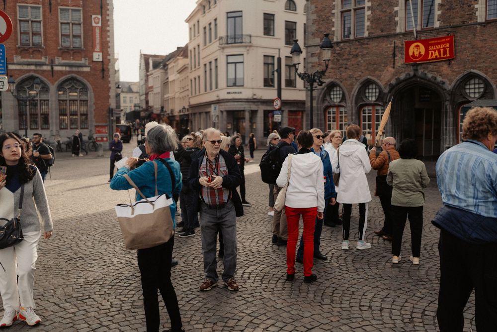 Tourists gather on a cobblestone street in a historic European city center.