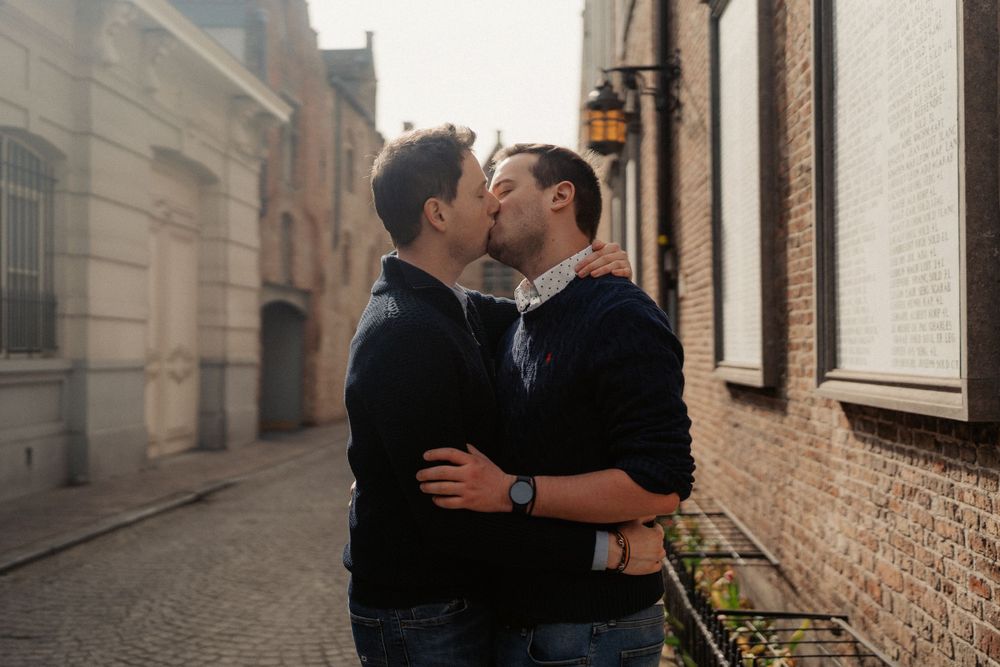 A couple shares a tender moment on a misty street in a historic town setting.