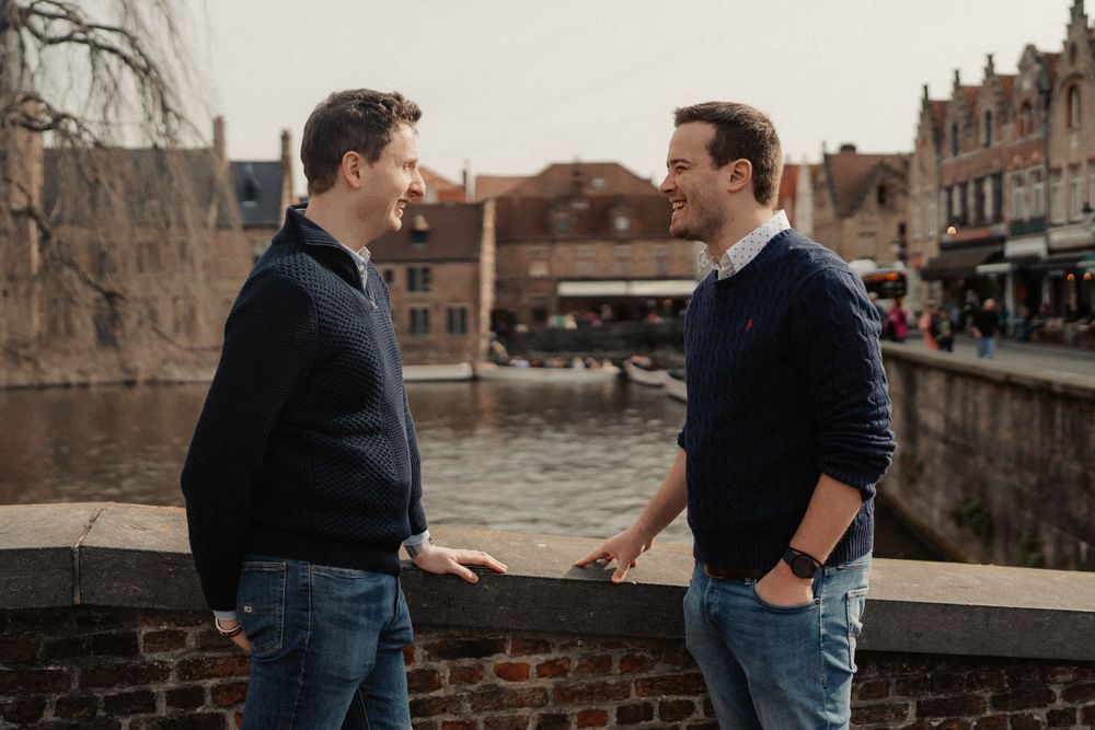 Two people walk past shops and cafes on a charming European street.