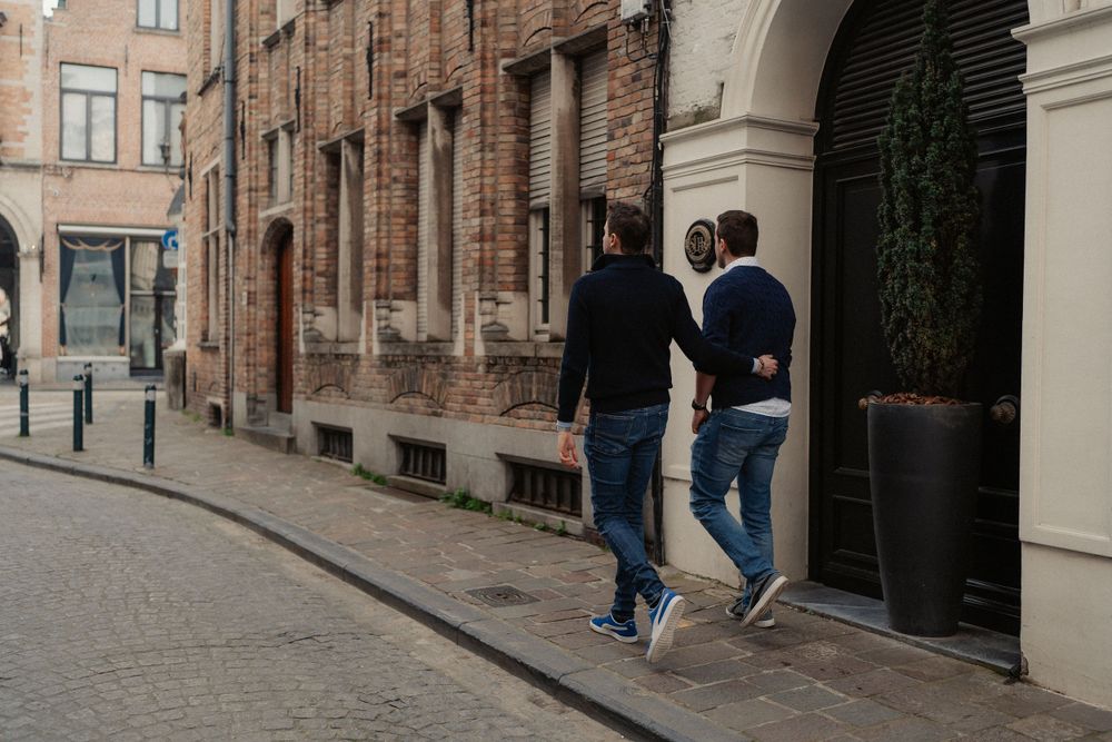 Two people walking along a historic street with traditional buildings and archways.