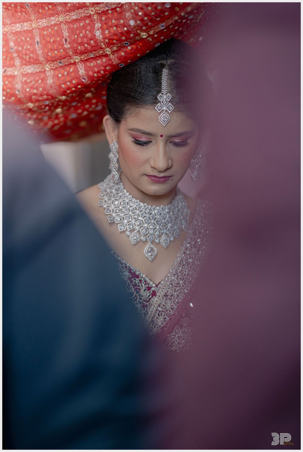 Close-up portrait of bride wearing traditional diamond jewelry and embellished wedding attire.