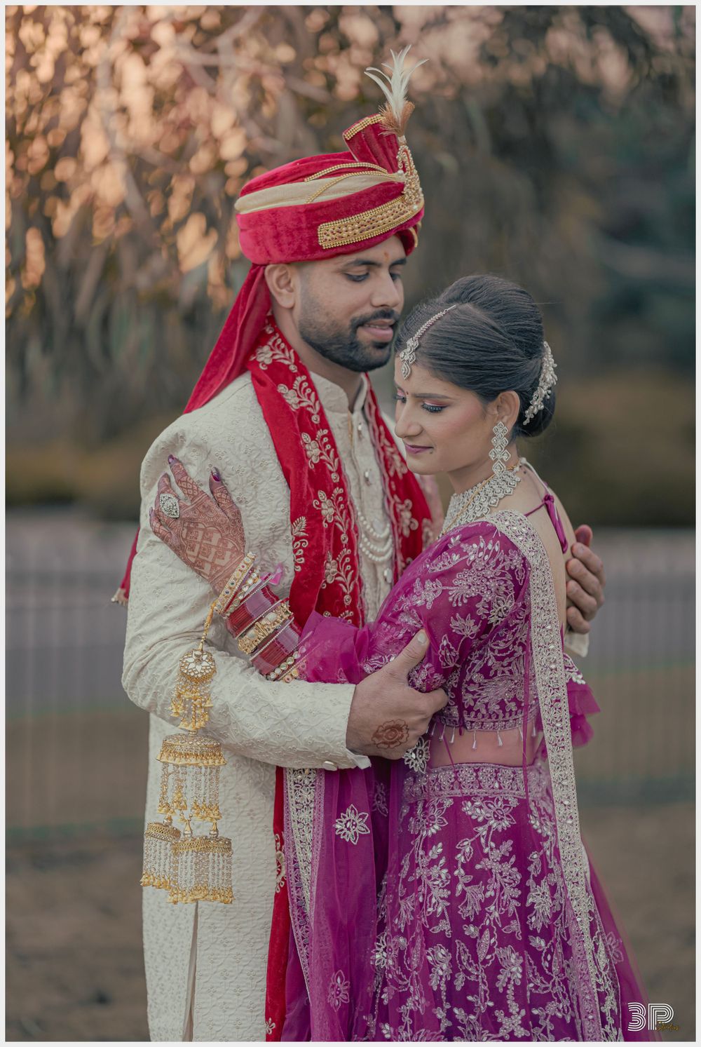 Couple in traditional Indian wedding attire sharing an intimate moment outdoors.