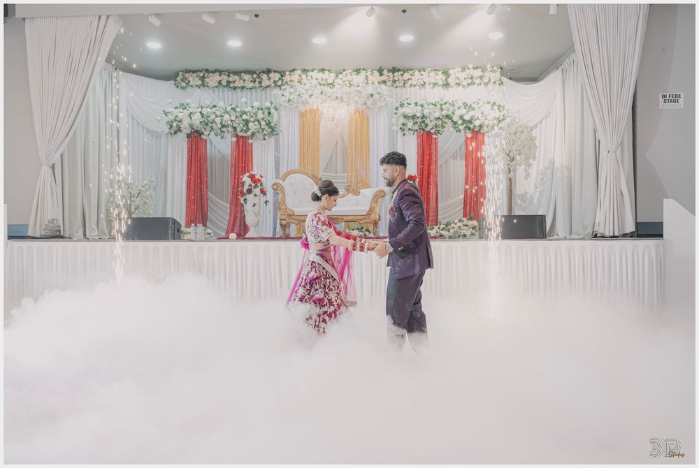Wedding couple dancing at decorated reception venue with white draping and floral decor.